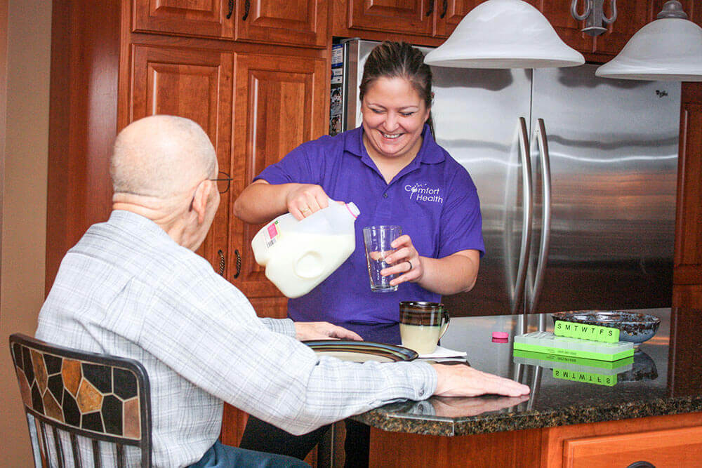 Nikki pouring a glass of milk for an older man in a kitchen