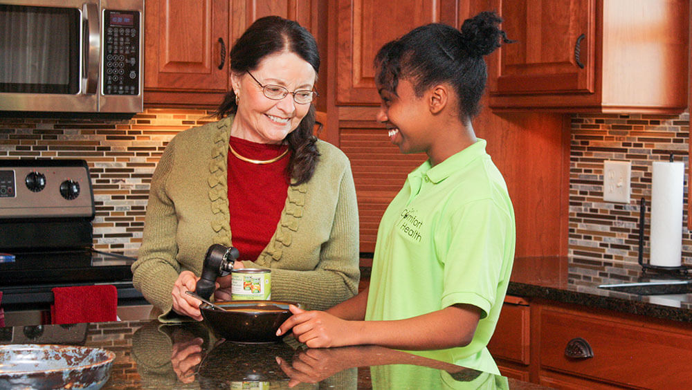 woman and caregiver in kitchen using a can opener