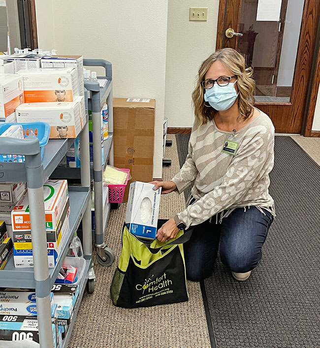 masked coman kneeling next to a cart of medical supplies